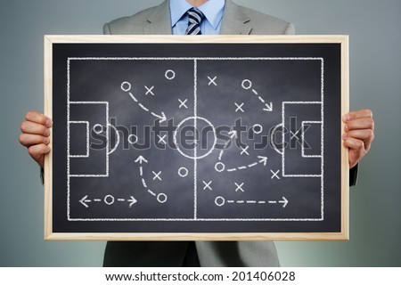 Business strategy businessman holding a blackboard planning team strategy on a chalk drawing of a soccer playing field