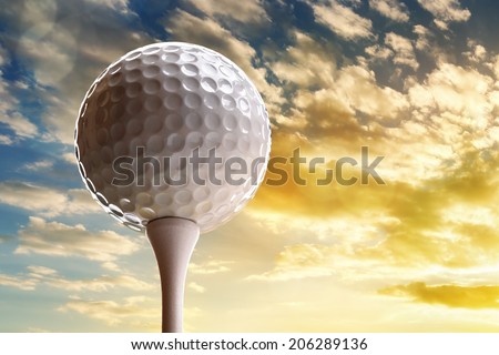 Golf ball on tee about to tee off against a sunset sky