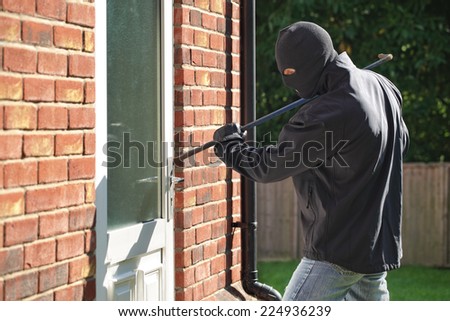 Burglar breaking into a house via a door with a crowbar