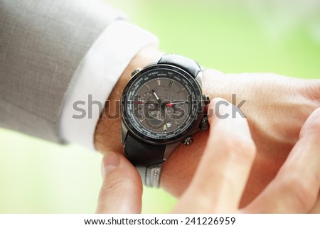 Businessman checking the time on his wrist watch concept for urgency, deadline or running late