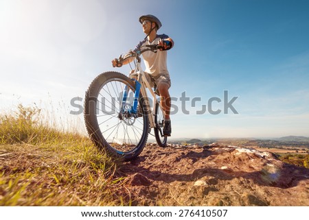 Mountain biker in action across rocks against blue sky concept for healthy lifestyle, exercise and extreme sports