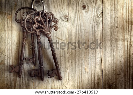 Old skeleton keys hanging against a wooden background