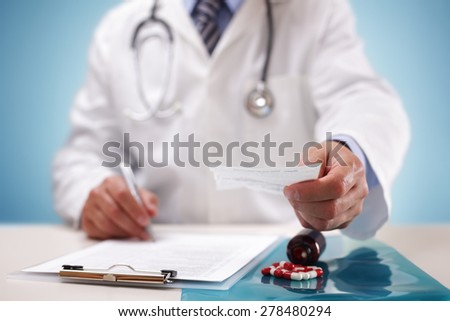 Doctor writing and holding a patient prescription after medical examination