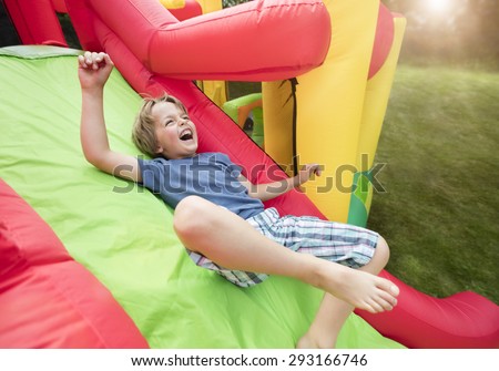 Boy jumping down the slide on an inflatable bouncy castle