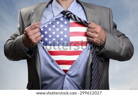 Businessman in classic superhero pose tearing his shirt open to reveal t shirt with the American flag concept for patriotism, freedom and national pride