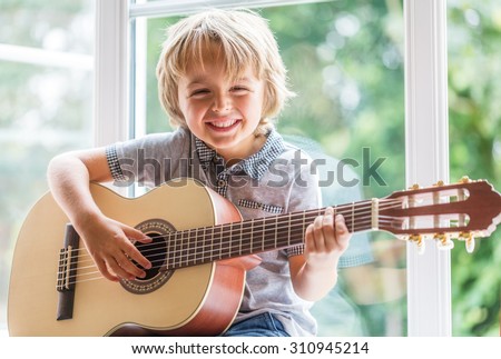 Happy smiling boy learning to play the acoustic guitar