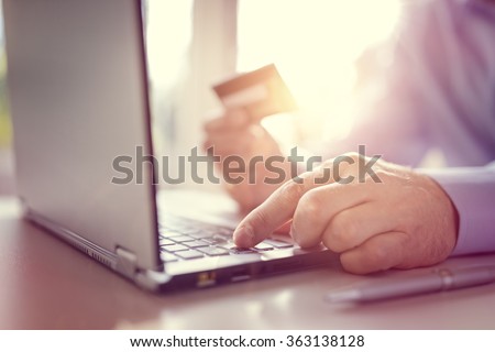 Man with credit card using a laptop computer for internet shopping