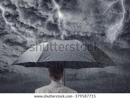 Businessman with black business umbrella protecting himself from the storm concept for insurance, financial protection from recession or economic depression