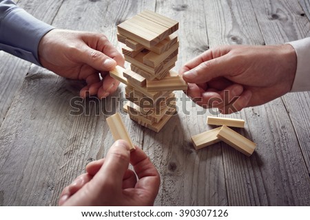 Planning, risk and team strategy in business, businessman gambling placing wooden block on a tower