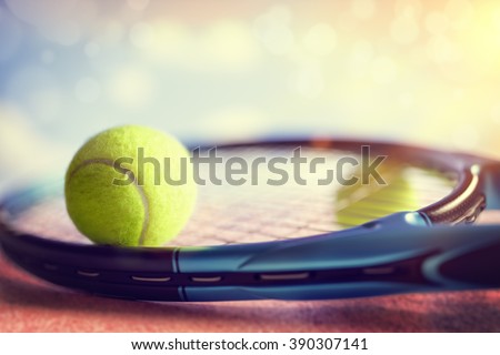Tennis ball resting on top of a tennis racquet on a red asphalt court