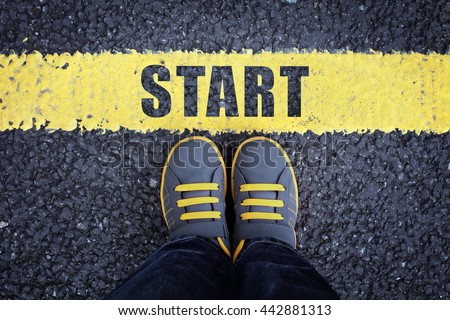 Start line child in sneakers standing next to a yellow starting line