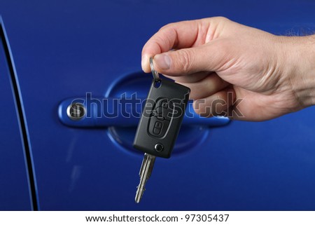 Car salesman or rental man giving a car key to a customer