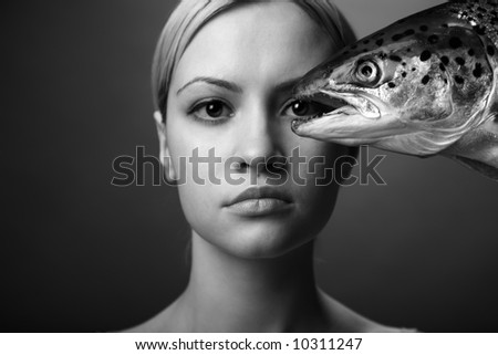 fashionable elegant girl with big fish on dark background