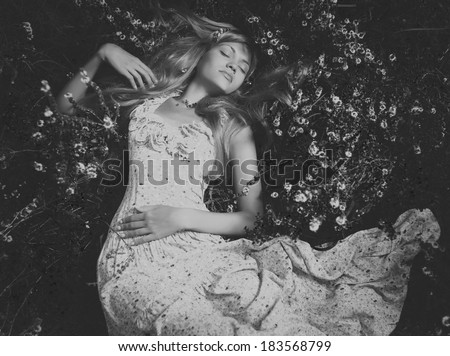 Black and white portrait of beautiful lady lying amond flowers