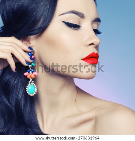 Fashion studio portrait of beautiful young woman with earring. Beauty and makeup. Jewelry and accessories