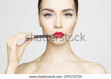 Studio fashion photo of beautiful young lady applied lipstick.  Perfect face makeup