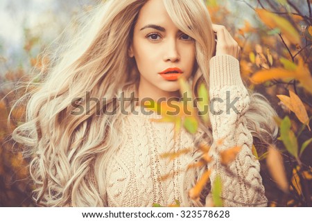 Outdoor fashion photo of young beautiful lady surrounded autumn leaves