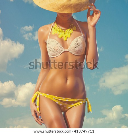 Outdoors fashion photo of young lady with perfect body in swimsuit against the sky