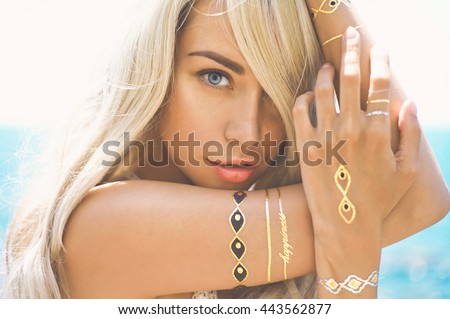 Outdoor fashion portrait of beautiful blonde lady at beach with flash tattoo