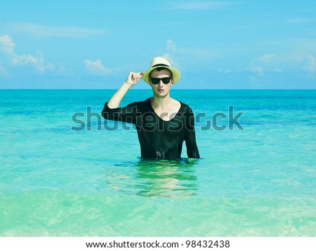 Young stylish man in the hat jumps on the sea