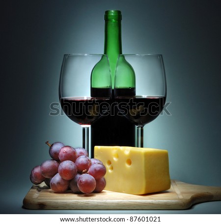The bottle with red wine, two glasses, cheese and grape