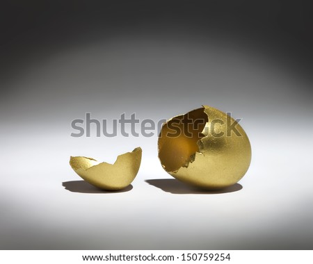 A golden cracked egg shell in a spotlight.