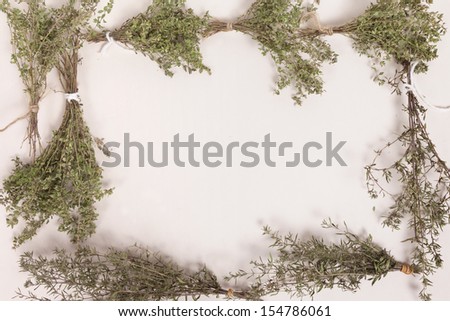 Bundles of drying thyme and savory herb create a frame against a white background with copy space.