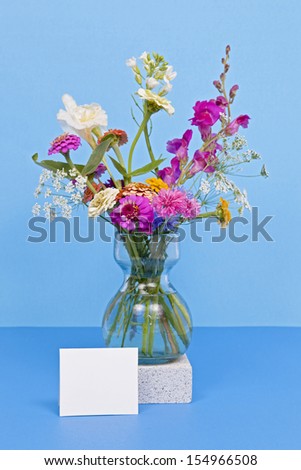 A vase of colorful wild flowers against a colorful solid background.