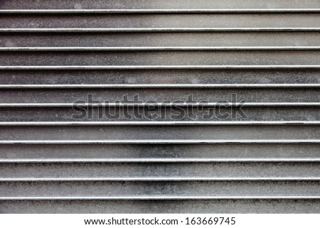 A flat wall with lots of detail and texture of horizontal metal stripes.