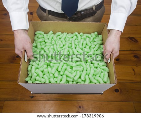 A caucasian male holding an office box full of packing peanut