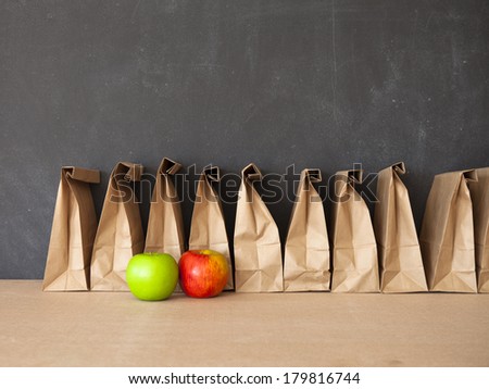 A row of brown bags against a blackboard.