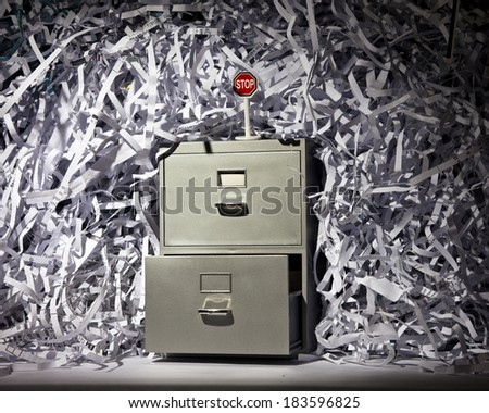 A file cabinet surrounded by lots of shredded paper with a stop sign.