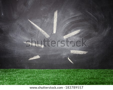 Blackboard with yellow chalk lines and fake green turf background.