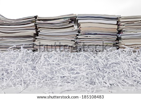 Tall stacks of magazines with shredded white paper against a white background.