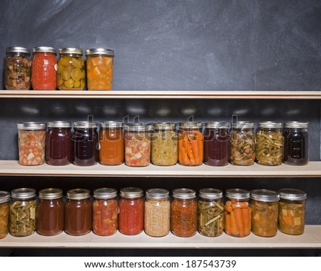 Canned goods on wooden shelves against a chalkboard.