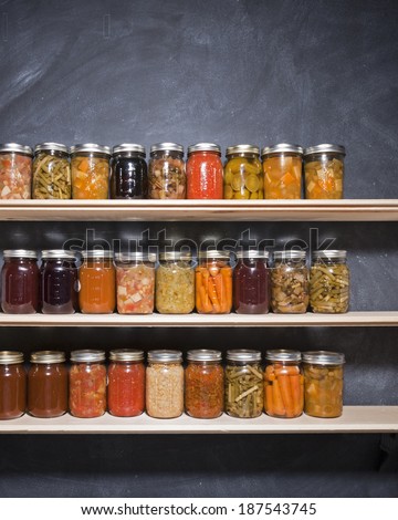 Canned goods on wooden shelves against a chalkboard.