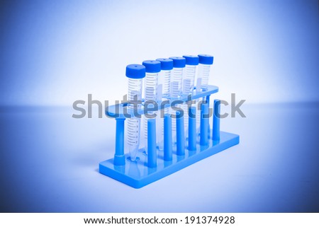 Test tubes in a test tube holder against a white background with a blue tinted filter and a vignette.