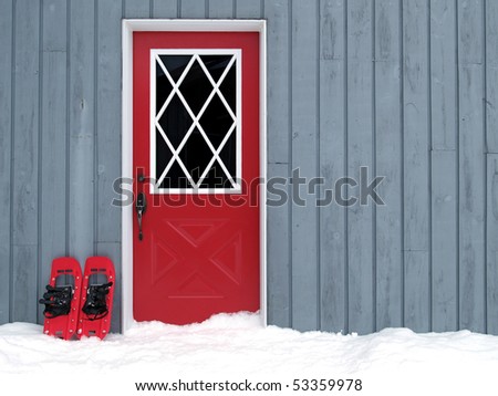 red snowshoes beside a red door in a paneled wall