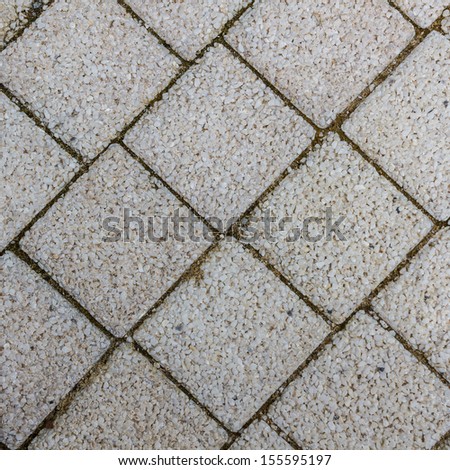 Paving slabs in the form of squares. Small gravel surface.