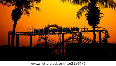 Roller coaster silhouette at sunset in the theme park.