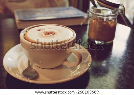 Coffee cup on the wooden table in the coffee shop - vintage style effect picture.