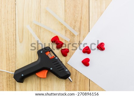 Closeup electric hot glue gun apply the glue to making postcard with red heart.