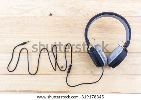 Black Headphones on wood desk Background.