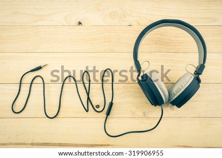 Black Headphones on wood desk Background. Vintage color tone.