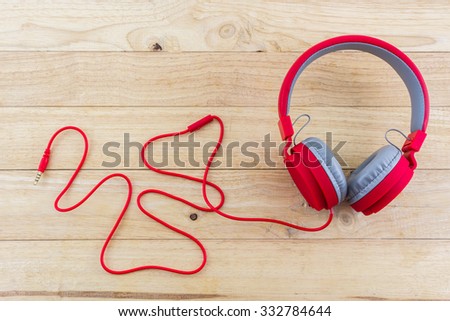 Red Headphones on wood desk Background.