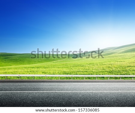 asphalt road and perfect green field