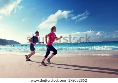 Man And Women Running On Tropical Beach At Sunset