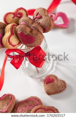 Homemade heart shape cookies on a stick in a glass.