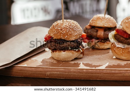 Three Mini Burgers Sliders On Rustic Wooden Plate