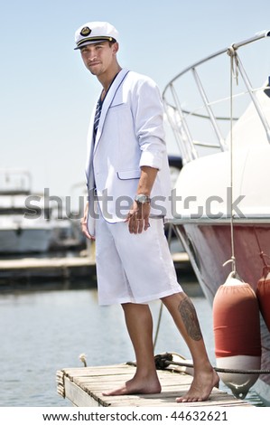 Attractive young captain over the jetty beside his boat